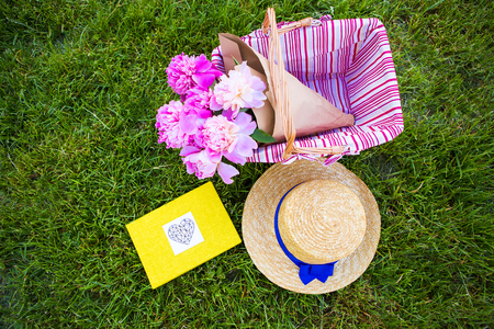 Beautiful flowers in a basket and yellow album lie on the grass-bright picnicの写真素材