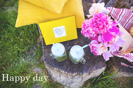 Beautiful basket stands on a wooden stump with flowers and drinks-inscription happy dayの写真素材