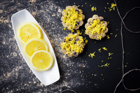 lemon cupcakes on a black background and a lemon on a plateの写真素材