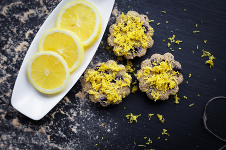 lemon cupcakes on a black background and a lemon on a plateの写真素材