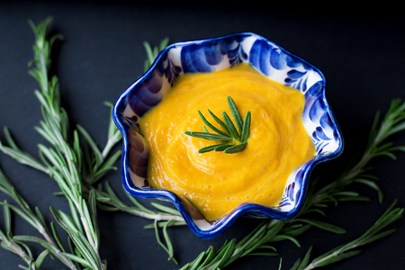 pumpkin soup on a black background with the sprigs of rosemary, close-up.の写真素材