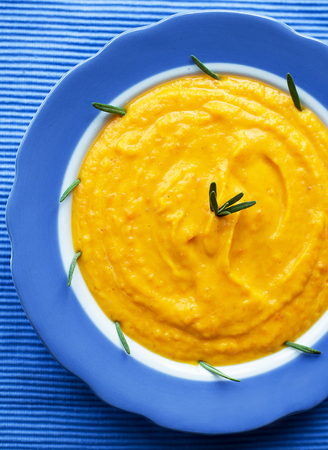 pumpkin cream soup in a blue plate on blue napkin.の写真素材