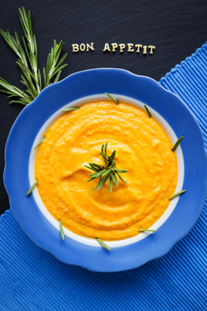 pumpkin soup in a blue plate on a black background with a blue napkin.の写真素材