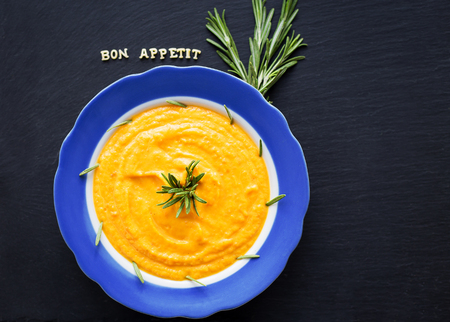 pumpkin soup in a blue plate on a black background with a blue napkin.の写真素材