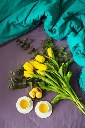 yellow tulips, cookies and two cups of tea in bed, close-upの写真素材