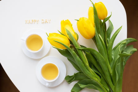 Beautiful yellow tulips on the table, the inscription happy dayの写真素材