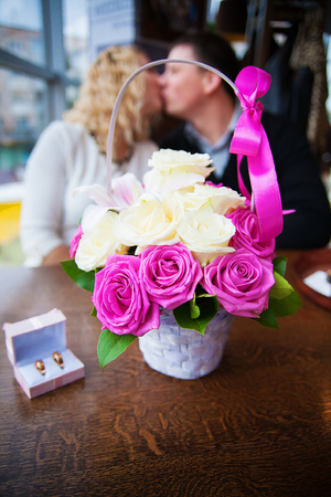 bouquet of flowers and wedding rings in a box on a background kissing couple.の写真素材
