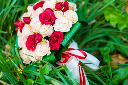 picture of a wedding bouquet , Wedding bouquet of red and white roses lying on grassの写真素材