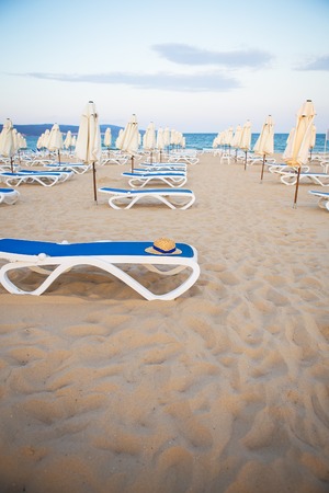 a straw hat rests on a deck-chair near the sea.の写真素材