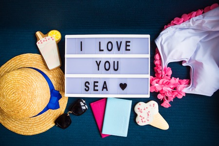 Summer layout-swimsuit, hat, sunglasses, passport, ice cream, cocktail-inscription I love the sea.