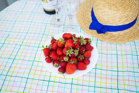 Romantic picnic - wine, strawberry and straw hat are on the table, close-up.の写真素材