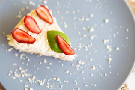 A piece of delicious and bright cheesecake, decorated with fresh strawberries and basil leaves.の写真素材