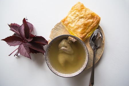 Soup with quail stands on a wooden stand along with pastries.の写真素材