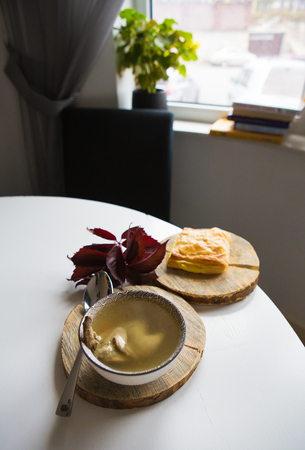 Soup with quail stands on a wooden stand along with pastries.の写真素材