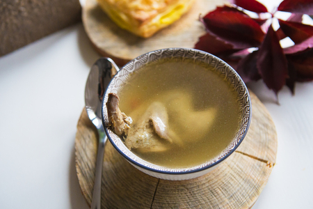 Soup with quail stands on a wooden stand along with pastries. Close-upの写真素材