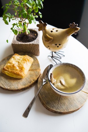 Soup with quail stands on a wooden stand and cheese pastries near the windowの写真素材