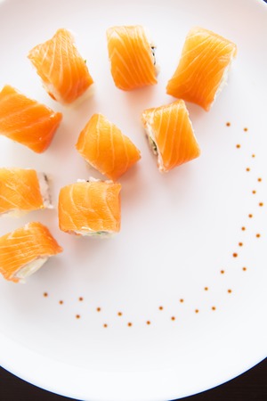 Sushi roll with salmon, philadelphia on a white plate, top view. Close-up. Beautifully decorated plateの写真素材
