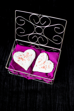 Cookies in the form of heart lies in a casket with pink cloth.の写真素材