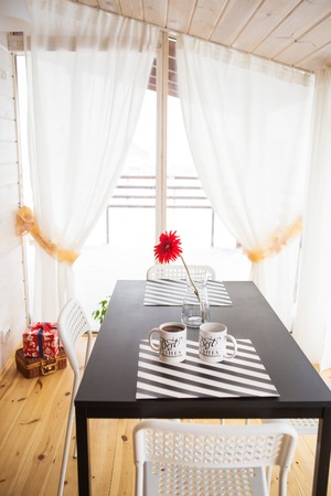 Beautiful and bright kitchen studio in the Scandinavian style, bright house. Vase and a cup of coffee on the tableの写真素材