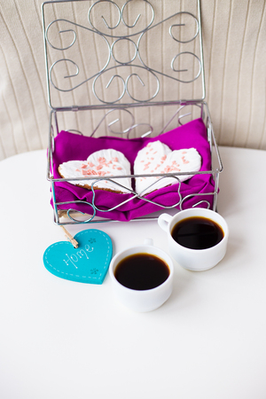 Cookies in a heart and two cups of coffee on the table that says home.の写真素材