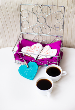 Cookies in a heart and two cups of coffee on the table that says home.の写真素材