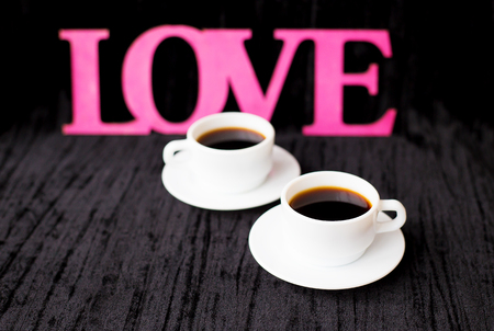 two cups of coffee on pink background inscription love.の写真素材