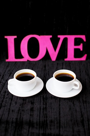 two cups of coffee on pink background inscription love Valentine's Day.の写真素材
