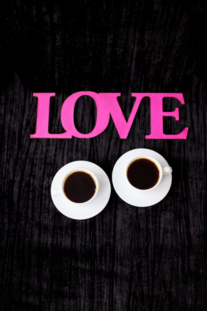 two cups of coffee on pink background inscription love Valentine's Day.の写真素材