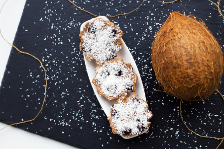 Sweet coconut muffins with chocolate on a white plate. Black backgroundの写真素材