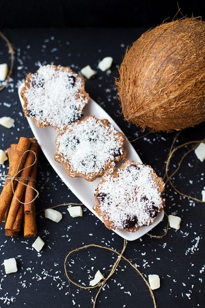 coconut muffins on a black background with cinnamon sticks and whole coconut slices and candiedの写真素材