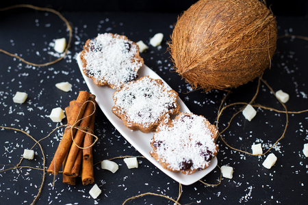 coconut muffins on a black background with cinnamon sticks and whole coconut slices and candiedの写真素材