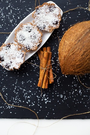 coconut muffins with chocolate on a black background and whole coconut, close upの写真素材