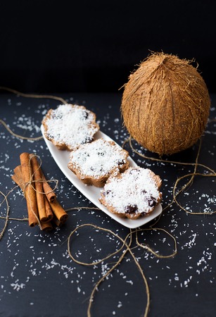 coconut muffins on a black background with cinnamon sticks and whole coconutの写真素材
