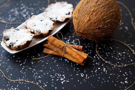 coconut muffins with chocolate and cinnamon on a black background and whole coconutの写真素材