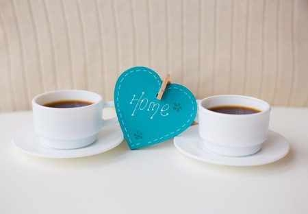 two cups of coffee on the table that says home.の写真素材