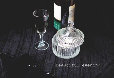 Sweets dishes, bottle and a glass of red wine on a black background - the inscription wonderful evening.の写真素材