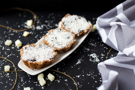coconut muffins on a black background with candied coconut and gray clothの写真素材
