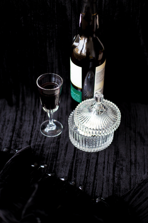 Sweets dishes, bottle and a glass of red wine on a black background.の写真素材