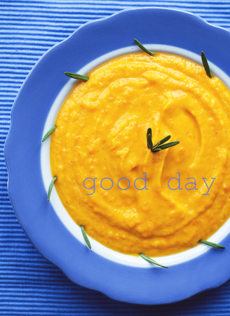 pumpkin cream soup in a blue plate on blue napkin. inscription good dayの写真素材