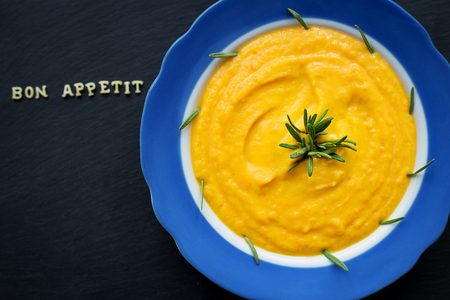 pumpkin soup in a blue plate on a black background, close-upの写真素材
