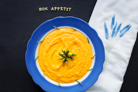pumpkin soup in a blue plate on a black background, close-upの写真素材