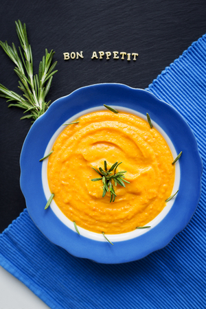 pumpkin soup in a blue plate on a black background with a blue cloth, close-upの写真素材