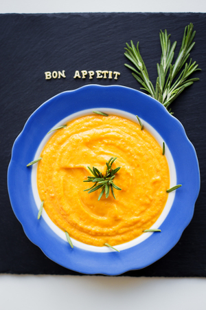pumpkin soup in a blue plate on a black background with a blue napkinの写真素材