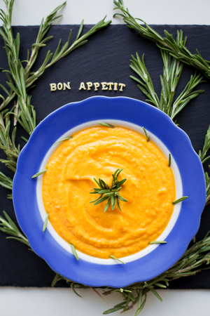 pumpkin soup with rosemary branches on a black background with a blue napkinの写真素材