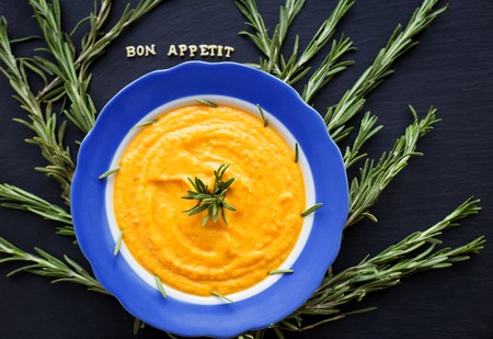 pumpkin soup with rosemary branches on a black background with a blue napkinの写真素材