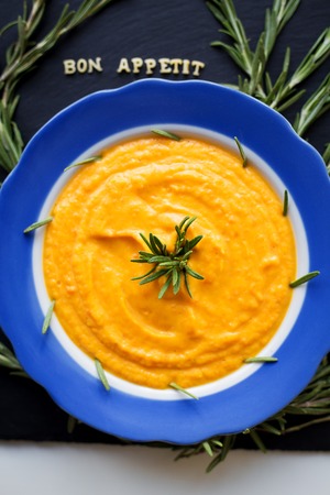 pumpkin soup with rosemary branches on a black background with a blue napkinの写真素材