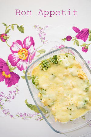 tasty casserole with broccoli on colorful napkin with pink flowers, lettering deliciousの写真素材