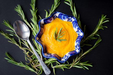 pumpkin soup on a black background with the sprigs of rosemary, close-upの写真素材