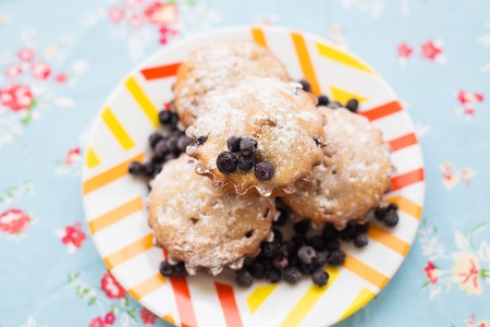 Blueberry muffins on plate and bright floral clothの写真素材