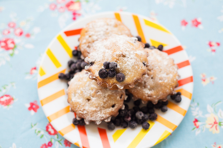 Blueberry muffins on plate and bright floral clothの写真素材